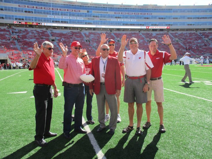 Sean Cleary and Barry Alvarez with other sponsor reps on the field at Camp Randall Stadium.