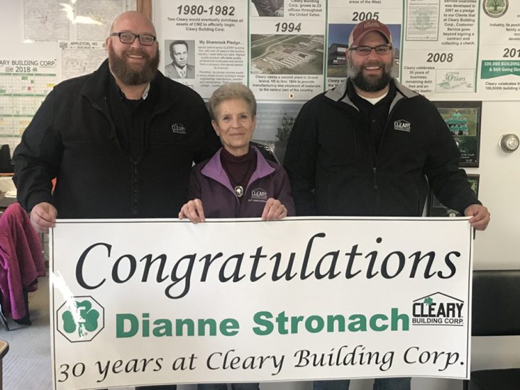 Dianne and two men hold a congratulatory banner.