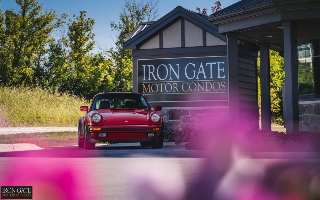 Iron Gate entrance with red sports car next to it.