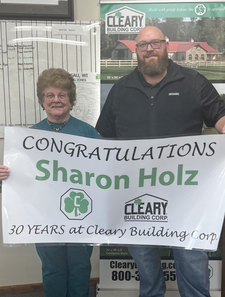 Scott Goodell and Sharon Holz hold anniversary banner.