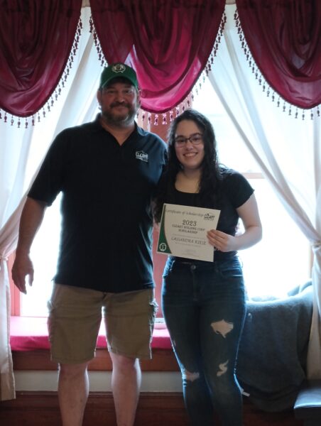 Cassandra holding her certificate while her dad, Dan, stands at her side.