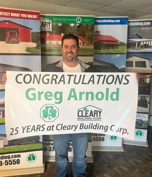 Greg Arnold Jr. holds up an anniversary banner.