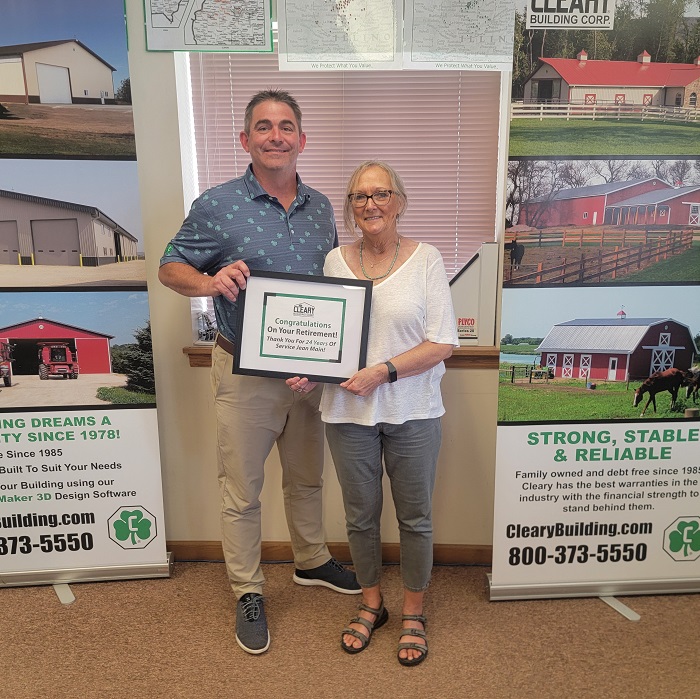 Jean is presented with a retirement certificate from Brian Ransom. They both smile at the camera.
